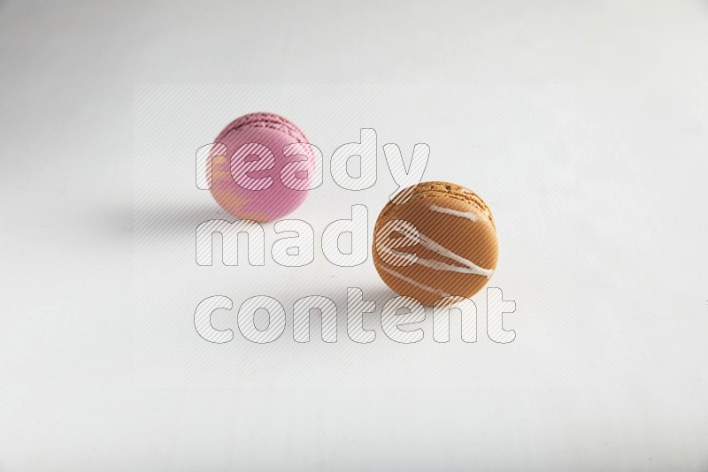 45º Shot of of two assorted Brown Irish Cream, and Purple Strawberry macarons on white background