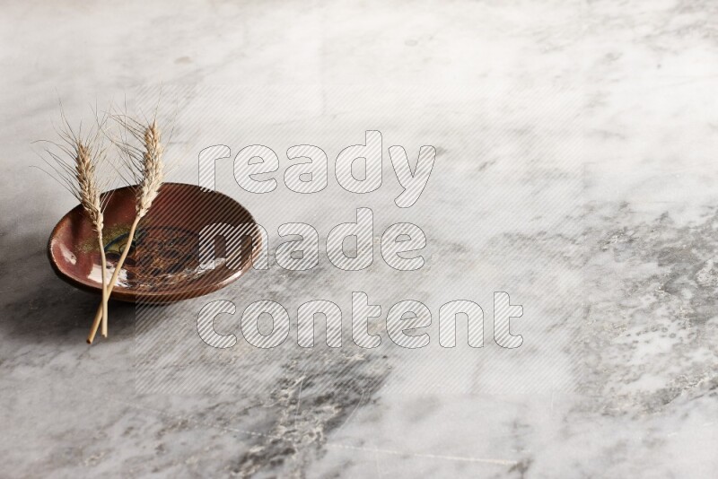 Wheat stalks on decorative pottery plate on grey marble background