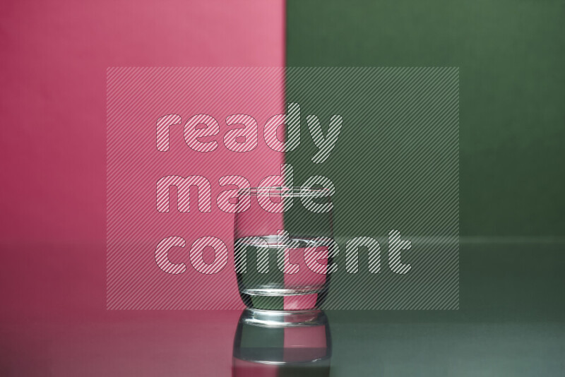 The image features a clear glassware filled with water, set against pink and dark green background