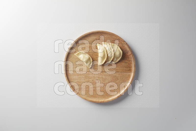 Four Sambosas on a wooden round plate on a white background