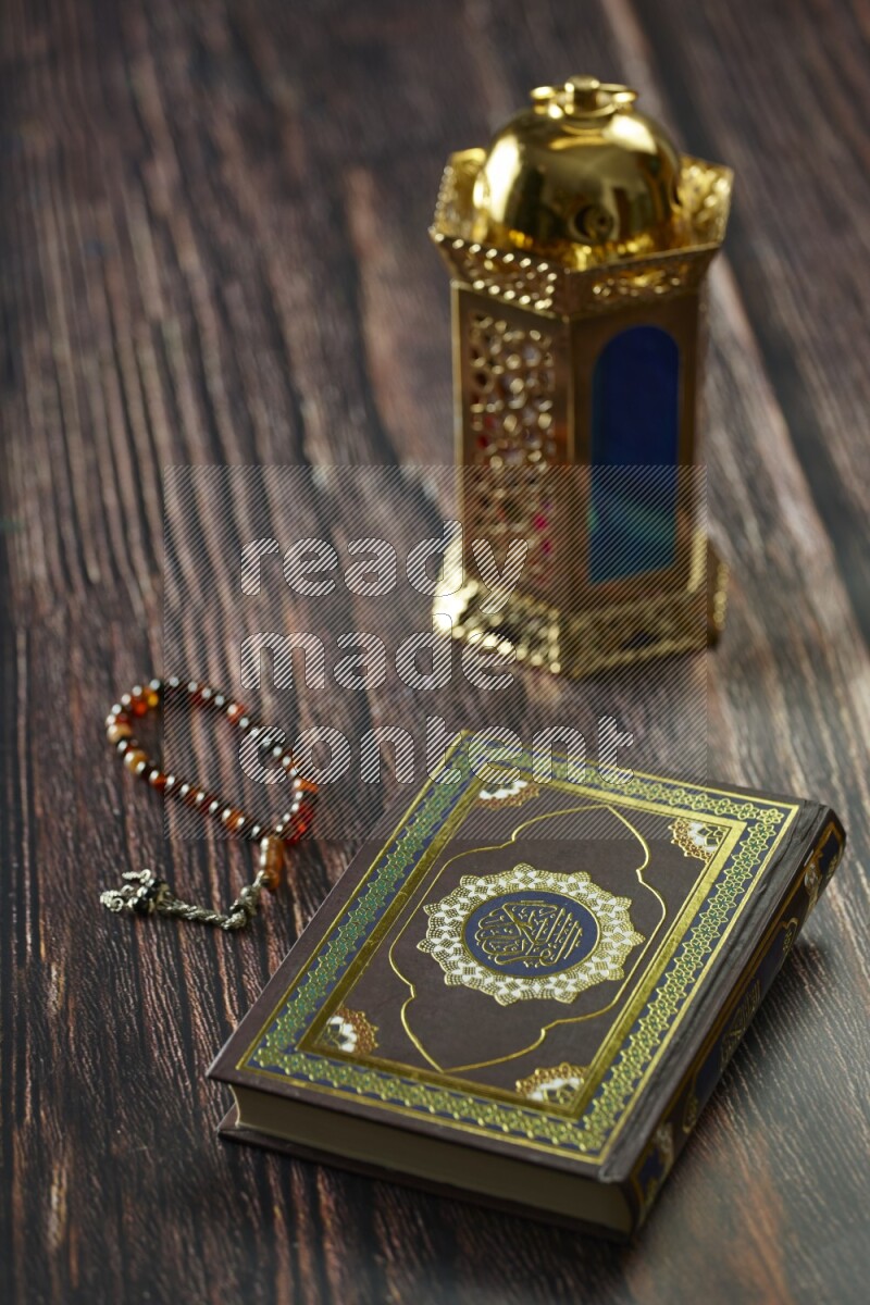 A golden lantern with different drinks, dates, nuts, prayer beads and quran on brown wooden background