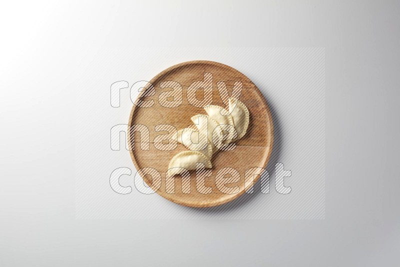 Five Sambosas on a wooden round plate on a white background