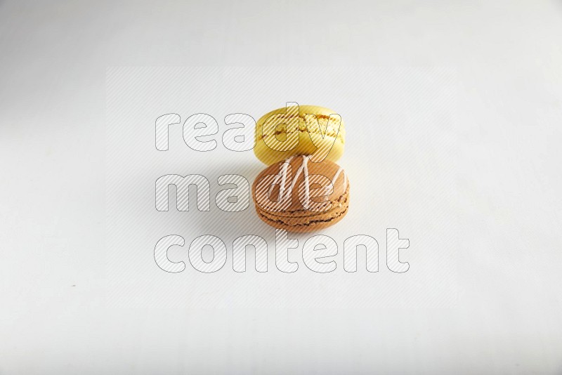 45º Shot of of two assorted Brown Irish Cream, and Yellow Lemon macarons on white background