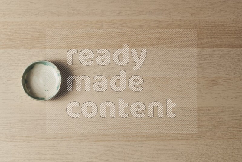 A multicolored pottery bowl on light wooden background