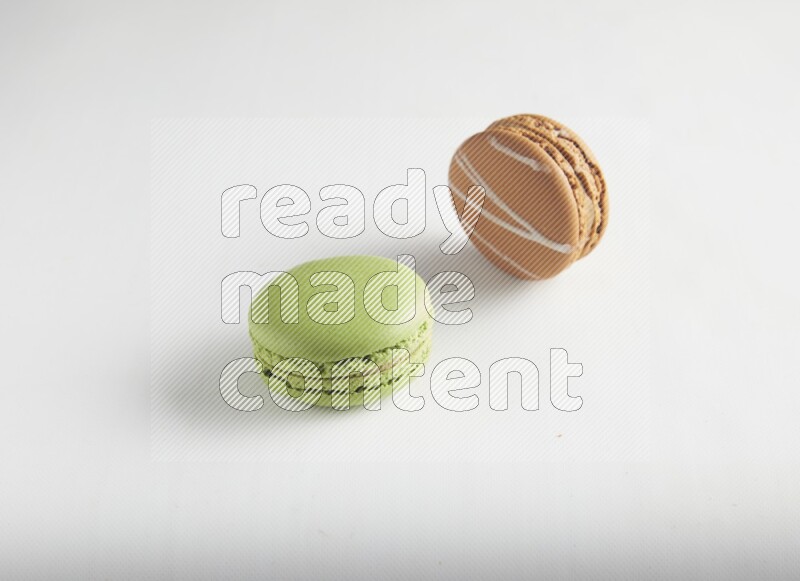 45º Shot of of two assorted Brown Irish Cream, and Green Pistachio macarons on white background