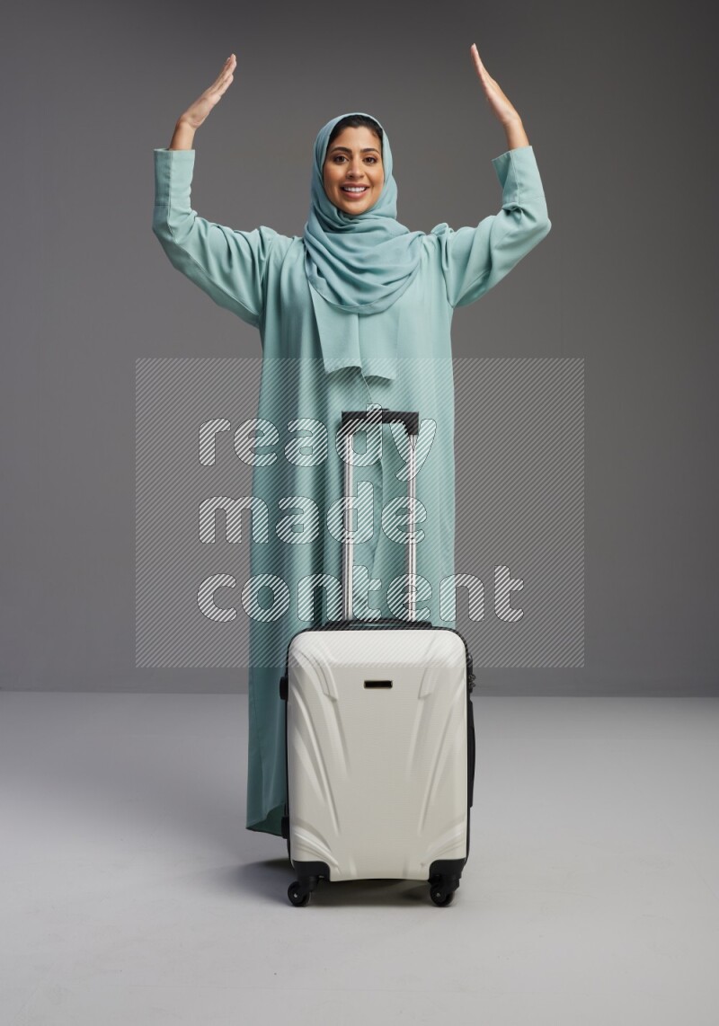 Saudi Woman wearing Abaya standing holding Travel bag on Gray background