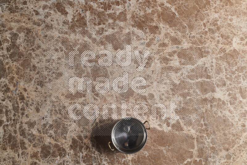 A small copper pot on beige marble background