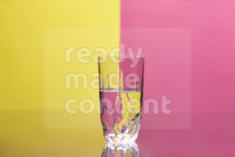The image features a clear glassware filled with water, set against yellow and pink background
