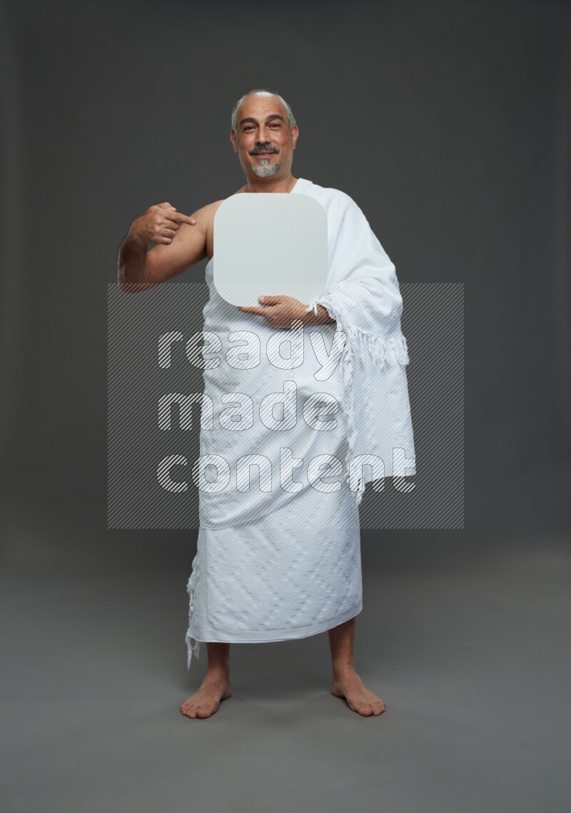 A man wearing Ehram Standing holding social media sign on gray background