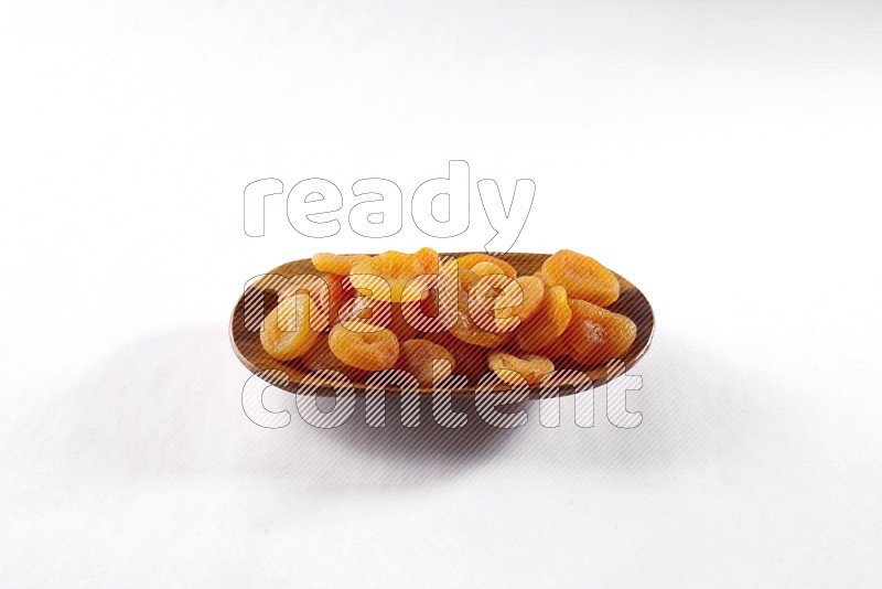 Dried apricots in a wooden plate on white background