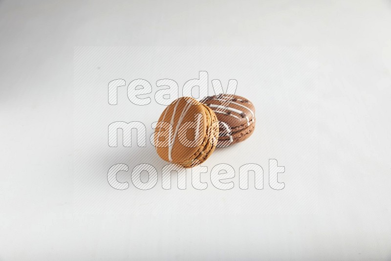 45º Shot of of two assorted Brown Irish Cream, and Brown white Chocolate Caramel macarons on white background