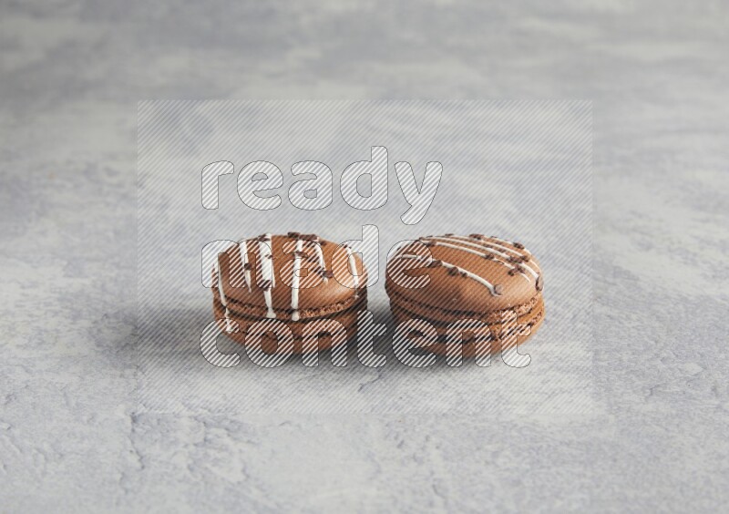 45º Shot of two Brown white marbleChocolate Caramel macarons  on white  marble background