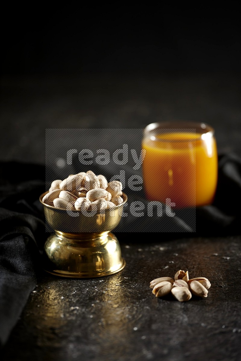 Nuts in a metal bowl with qamar eldin and a napkin in a dark setup