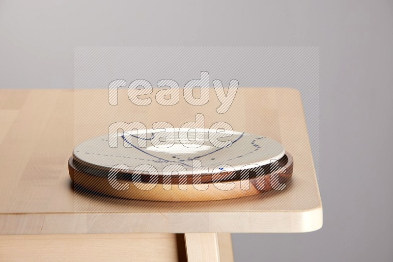 multi-colored pottery Plate placed on a light colored wooden tray on the edge of wooden table