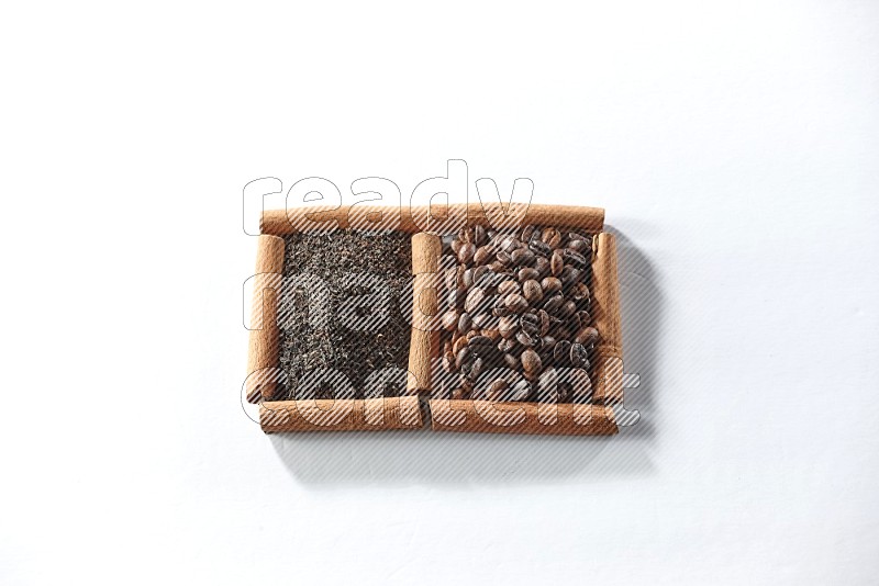 مربعان من أعواد القرفة ممتلئان بحبوب القهوة والشاي الأسود علي خلفية بيضاء