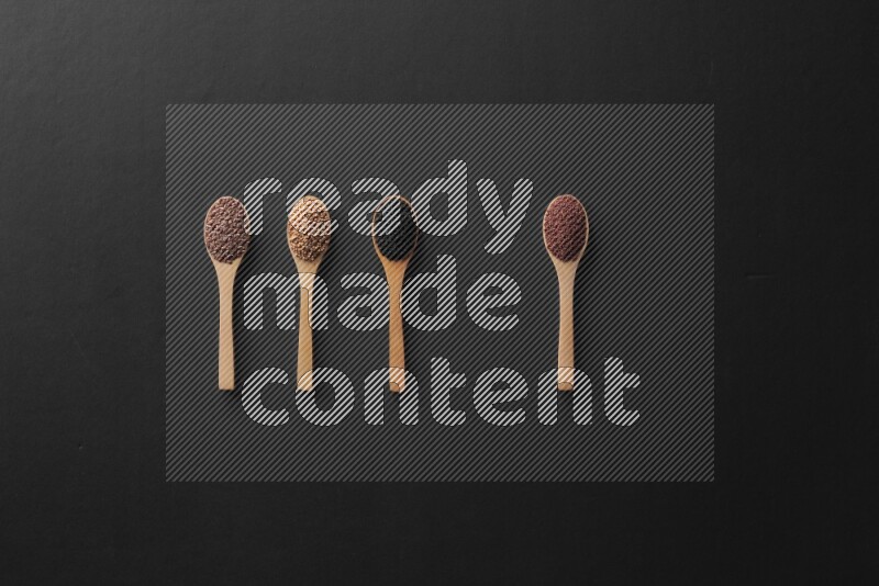 الفلفل الأسود وحبوب الخردل وحبة البركة وحب الرشاد والكمون و حبوب الكتان في معالق خشبية علي خلفية سوداء