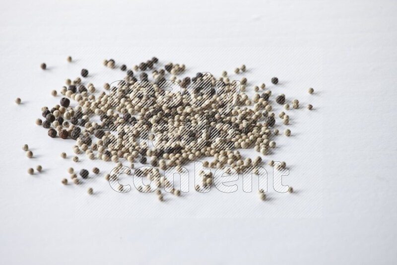 حبوب الفلفل المختلطة السوداء والبيضاء على أرضية بيضاء