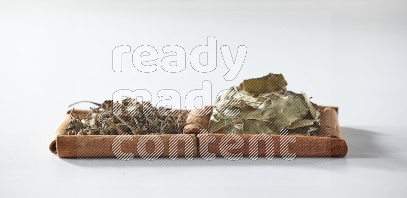 2 squares of cinnamon sticks full of dried basil and bay laurel leaves on white flooring