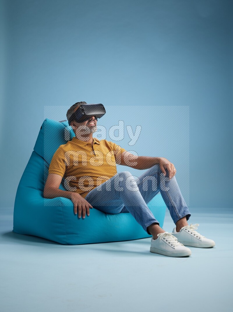 A man sitting on a blue beanbag and gaming with VR