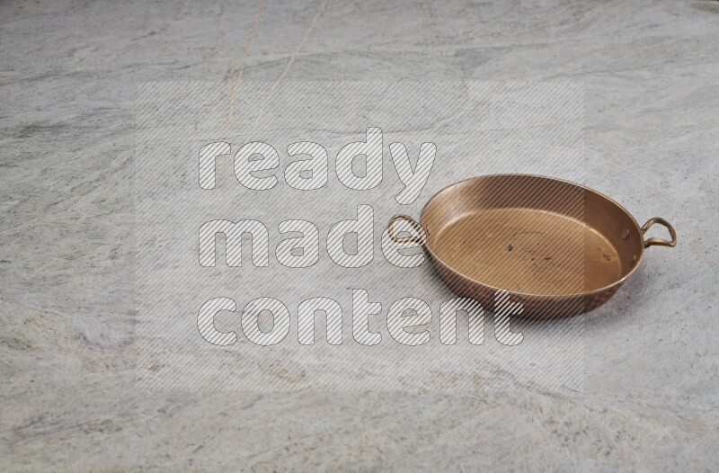 A small copper pan on grey marble background