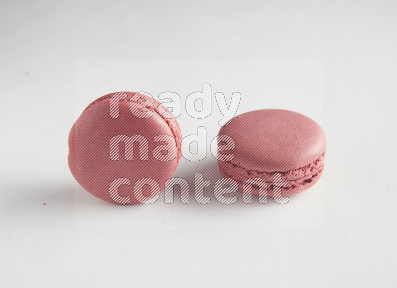 45º Shot of two Pink Raspberry macarons on white background