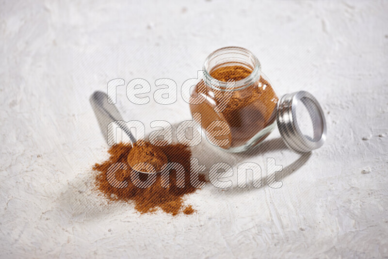 A glass jar full of ground paprika powder on white background