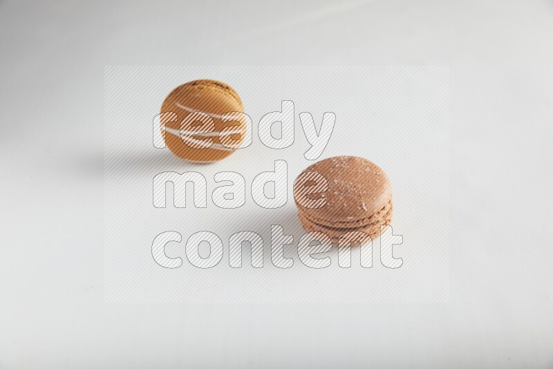 45º Shot of of two assorted Brown Irish Cream, and Brown Hazelnuts macarons on white background