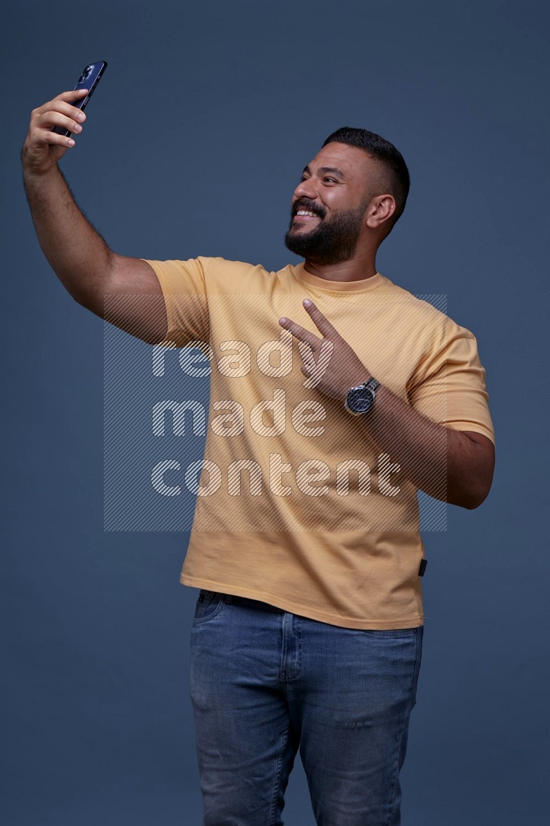 A man Taking A Selfie on Blue Background wearing Orange T-shirt