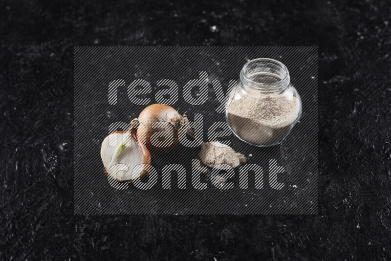 A glass jar full of onion powder on black background