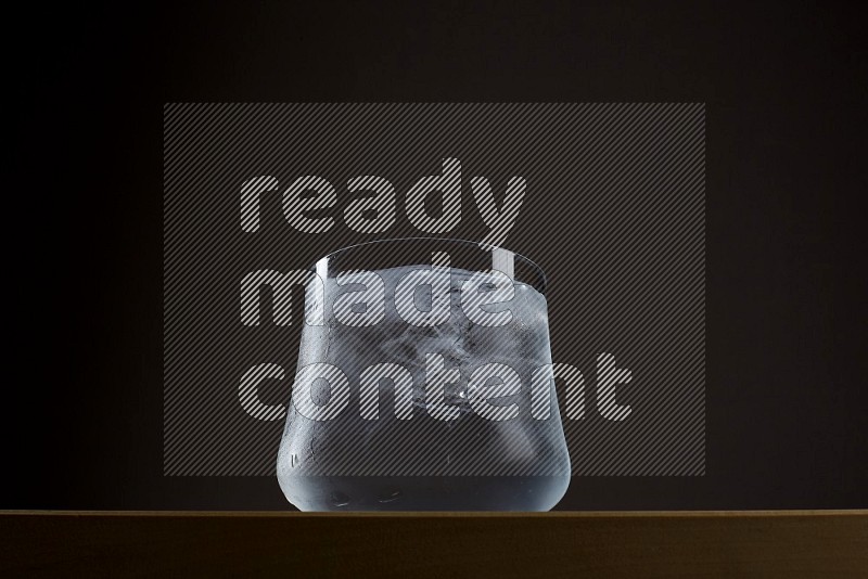 Low angle shot of a glass of water and ice on grey background