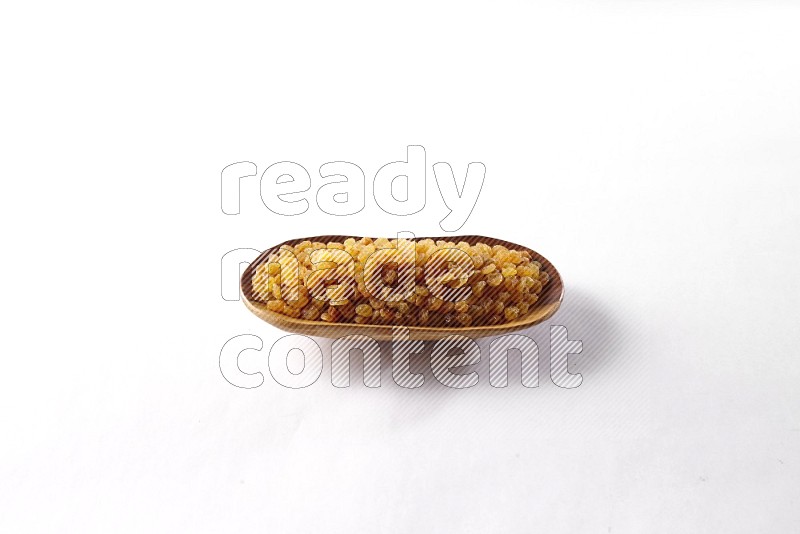 Raisins in a wooden plate on white background