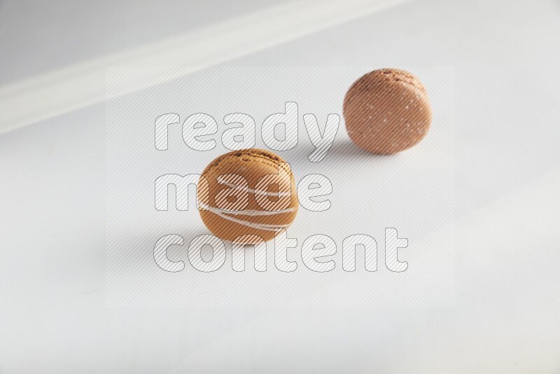 45º Shot of of two assorted Brown Irish Cream, and Brown Hazelnuts macarons on white background