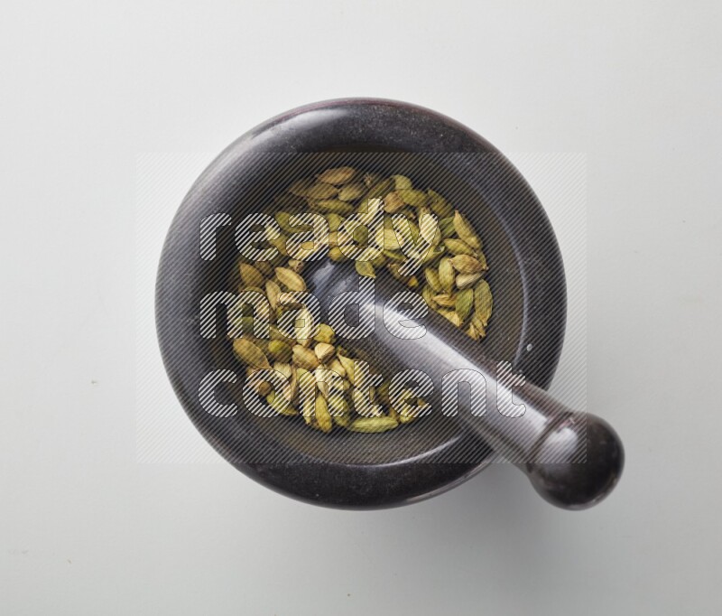 Top-view shot of Cardamon in herbs crusher on white background