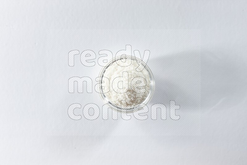 A glass bowl full of desiccated coconut on a white background in different angles