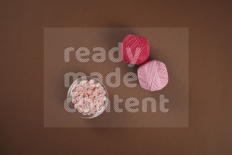 مجموعة من أدوات الخياطة والتفصيل زهرية اللون على خلفية بنية