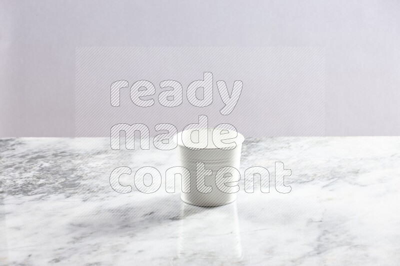 An empty white plant pot on grey marble background