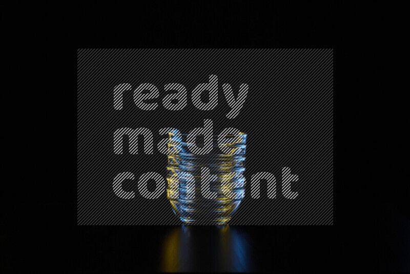 Glassware with rim light in blue and yellow against black background