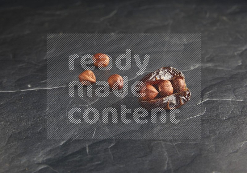 hazelnuts stuffed madjoul date on a black textured background