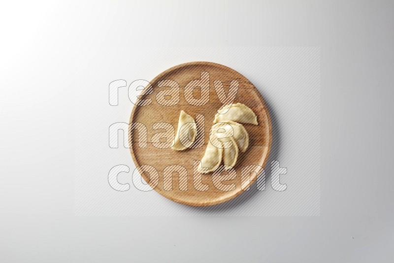 Five Sambosas on a wooden round plate on a white background