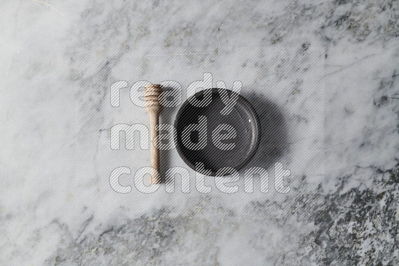 Black Pottery Bowl with wooden honey handle on the side on grey marble flooring, Top view