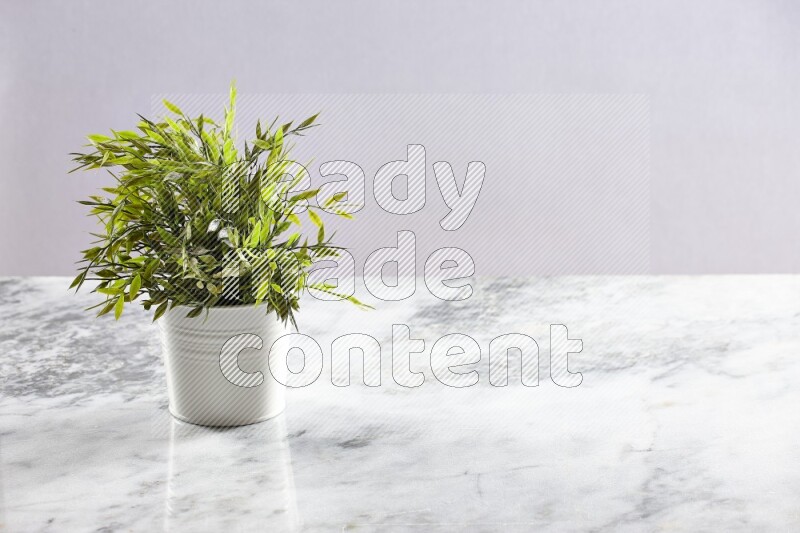 Green artificial plant in white pot on light grey marble background