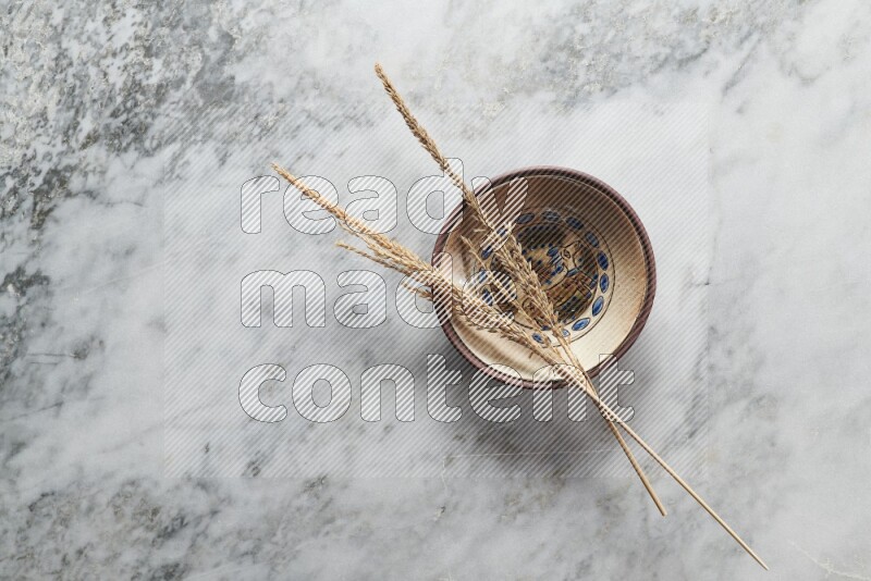 Wheat stalks on decorative pottery plate on grey marble background