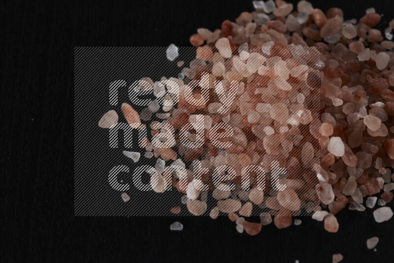 A bunch of coarse himalayan salt crystals on black background