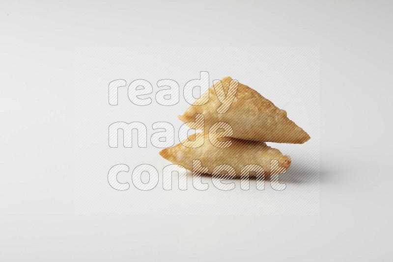 Two fried sambosas on a white background