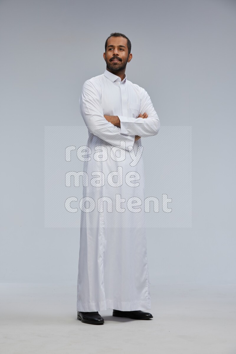 Saudi man wearing Thob standing with crossed arms on Gray background