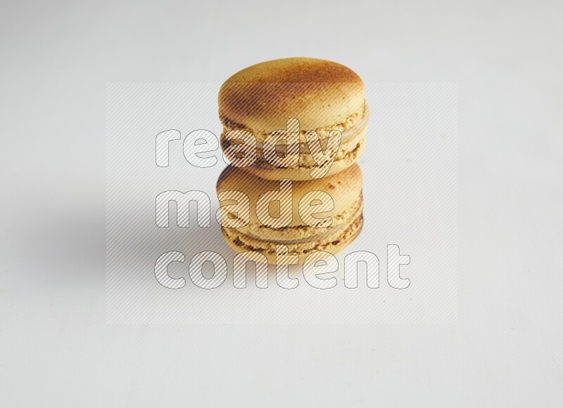 45º Shot of two Yellow Crème Brulée macarons on white background