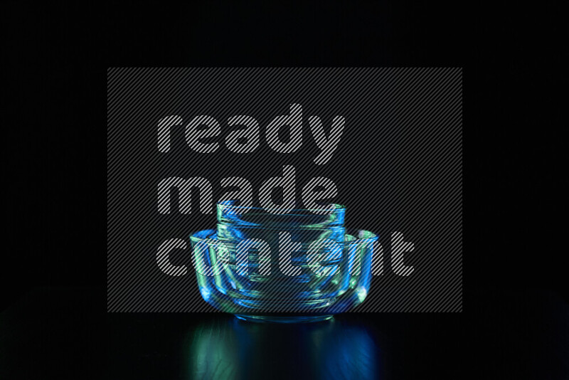 Glassware with rim light in blue and green against black background