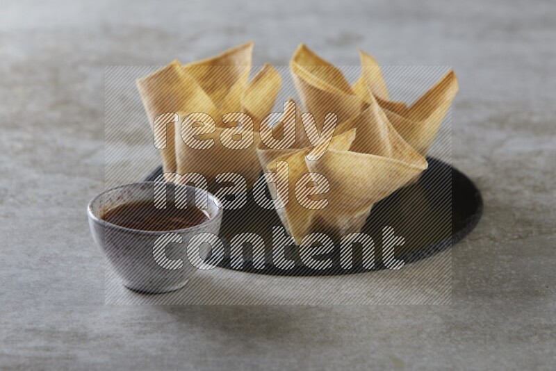 wonton cups with soy sauce ramkin on circle slate on grey textured counter top