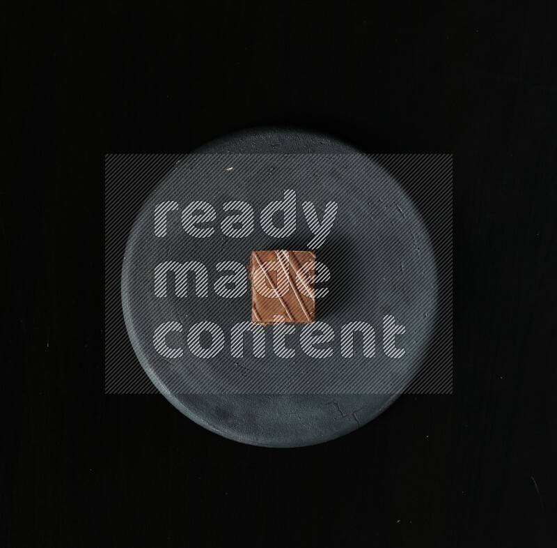 Assorted desserts in a black pottery plate on black background