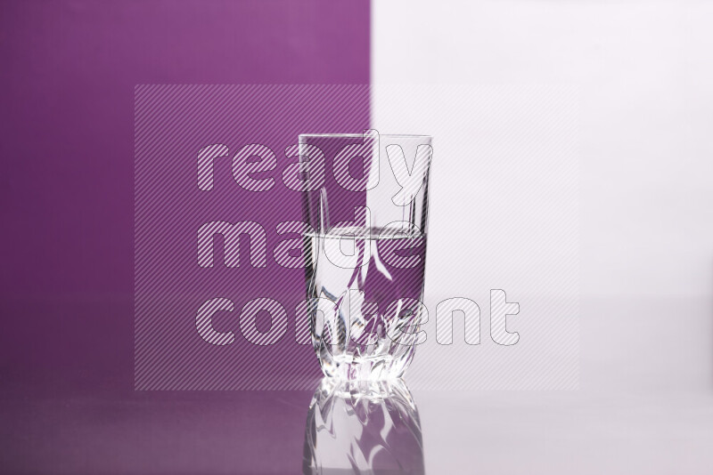 The image features a clear glassware filled with water, set against white and purple background